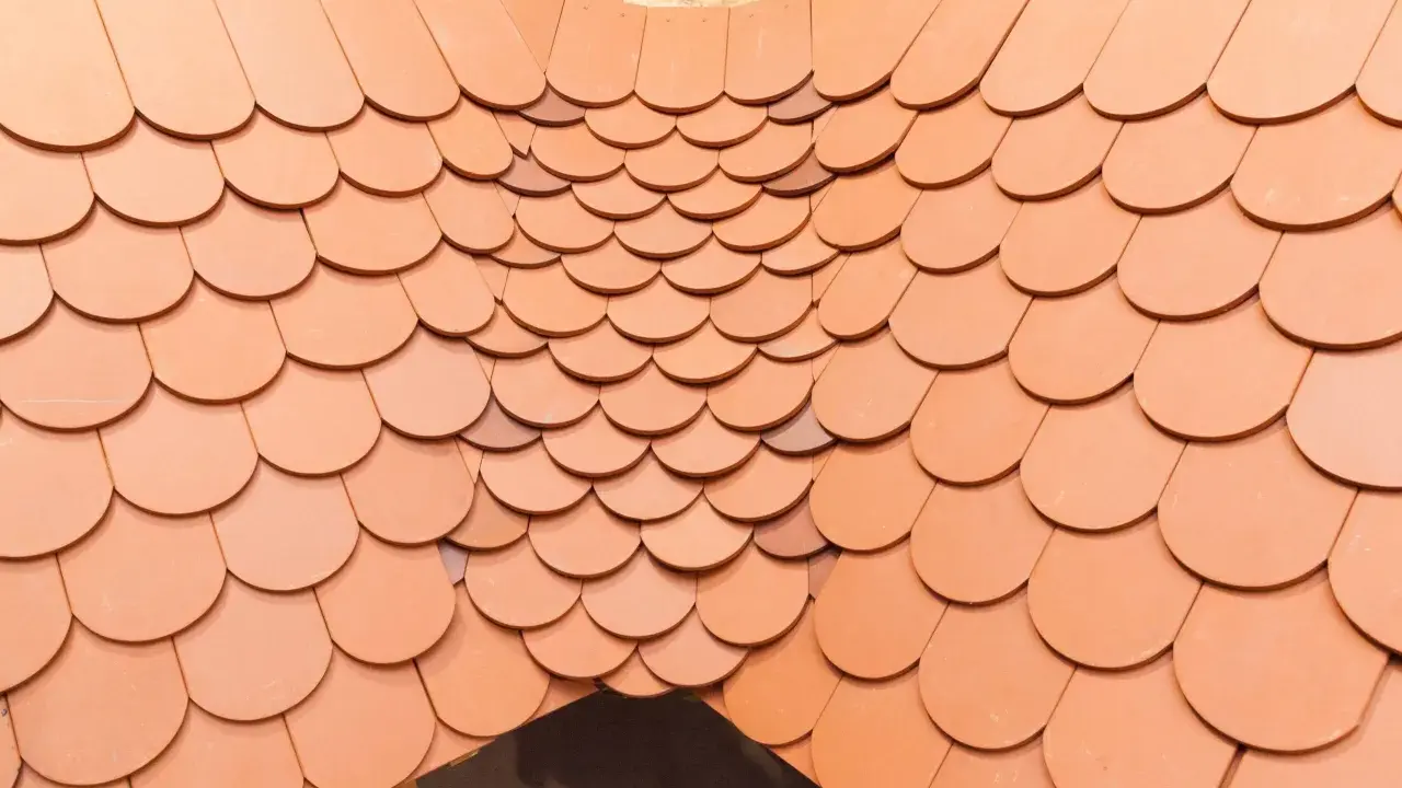 Obróbka kosza lukarny z dachówki ceramicznej. Widok z góry na ułożone dachówki, tworzące łukowaty kształt.