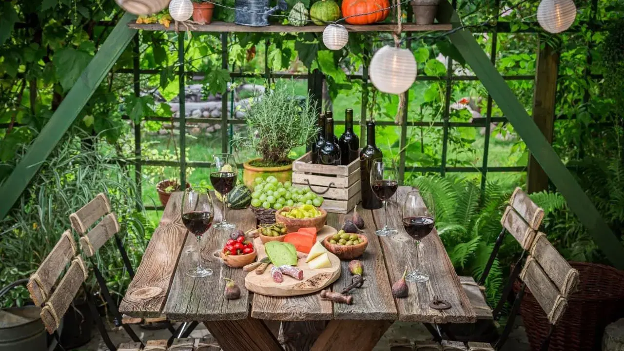 Stół ogrodowy gotowy na degustację wina i przekąsek. Idealne miejsce, by odpocząć i cieszyć się naturą.