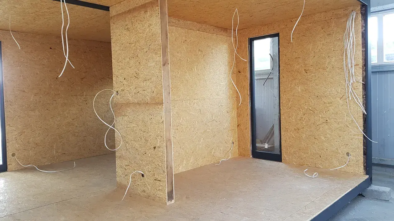 Budowa ścianki działowej z drewna: widok wnętrza z płyt OSB, instalacją elektryczną i oknem.