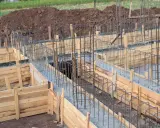 Drewniane deskowanie fundamentów z zbrojeniem stalowym, gotowe do zalania betonem.
