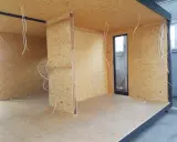 Budowa ścianki działowej z drewna: widok wnętrza z płyt OSB, instalacją elektryczną i oknem.