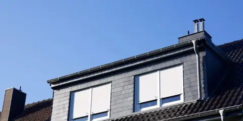 Dachówka kryje dom, a lukarna konstrukcja z dwoma oknami i roletami dodaje mu uroku.