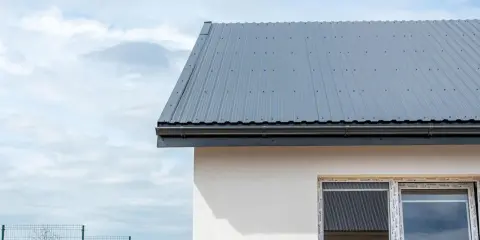 Nowy dach z szarej blachy, gotowy na deszcz. Układanie blachy na dachu zakończone.