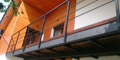 Nowoczesna balkon konstrukcja z czarną balustradą i drewnianymi elementami domu.