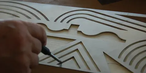 Ręka z ołówkiem zaznacza wzór na metalowym szablonie, który pomoże w precyzyjnym wykonaniu krokwi.