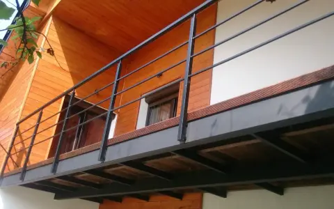 Nowoczesna balkon konstrukcja z czarną balustradą i drewnianymi elementami domu.