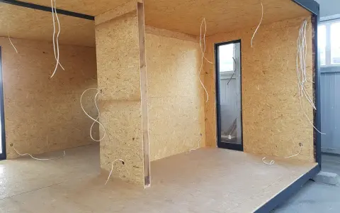 Budowa ścianki działowej z drewna: widok wnętrza z płyt OSB, instalacją elektryczną i oknem.