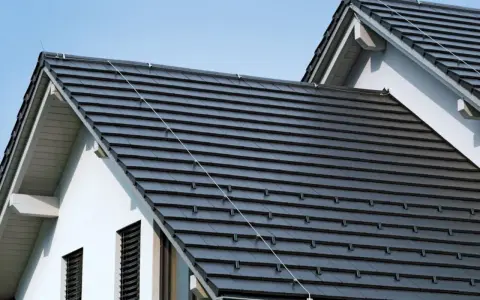 Nowoczesny dach z dachówki ceramicznej w ciemnym kolorze, chroniący dom przed deszczem i słońcem.