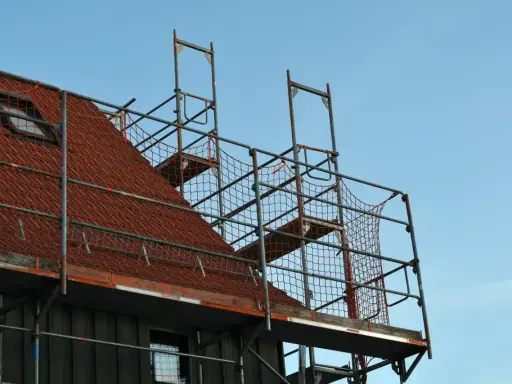 Metalowe rusztowanie na dachu z czerwonej dachówki, gotowe do prac remontowych.