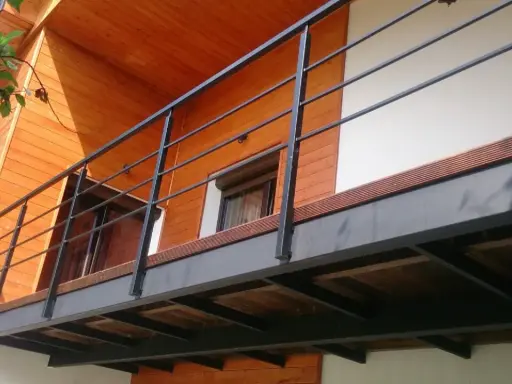 Nowoczesna balkon konstrukcja z czarną balustradą i drewnianymi elementami domu.