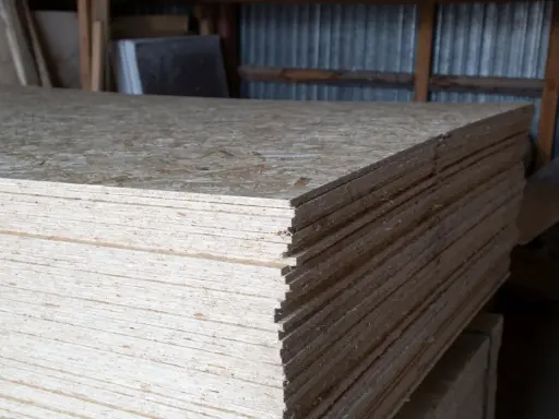Stos płyt OSB, grubość 18 mm, gotowych do użycia w budowie.