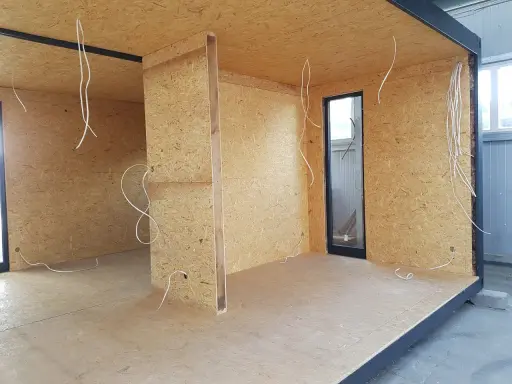 Budowa ścianki działowej z drewna: widok wnętrza z płyt OSB, instalacją elektryczną i oknem.