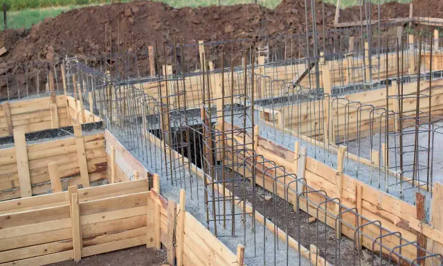 Drewniane deskowanie fundamentów z zbrojeniem stalowym, gotowe do zalania betonem.