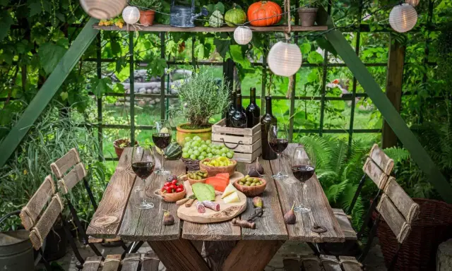Stół ogrodowy gotowy na degustację wina i przekąsek. Idealne miejsce, by odpocząć i cieszyć się naturą.