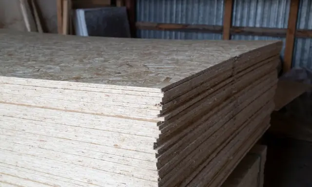 Stos płyt OSB, grubość 18 mm, gotowych do użycia w budowie.