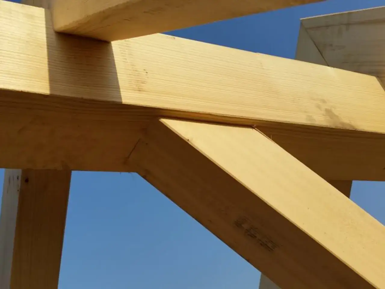Drewno KVH, czyli lite drewno strugane, tworzy solidną konstrukcję dachu na tle błękitnego nieba.